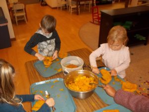 Children scooping pumpkin flesh.